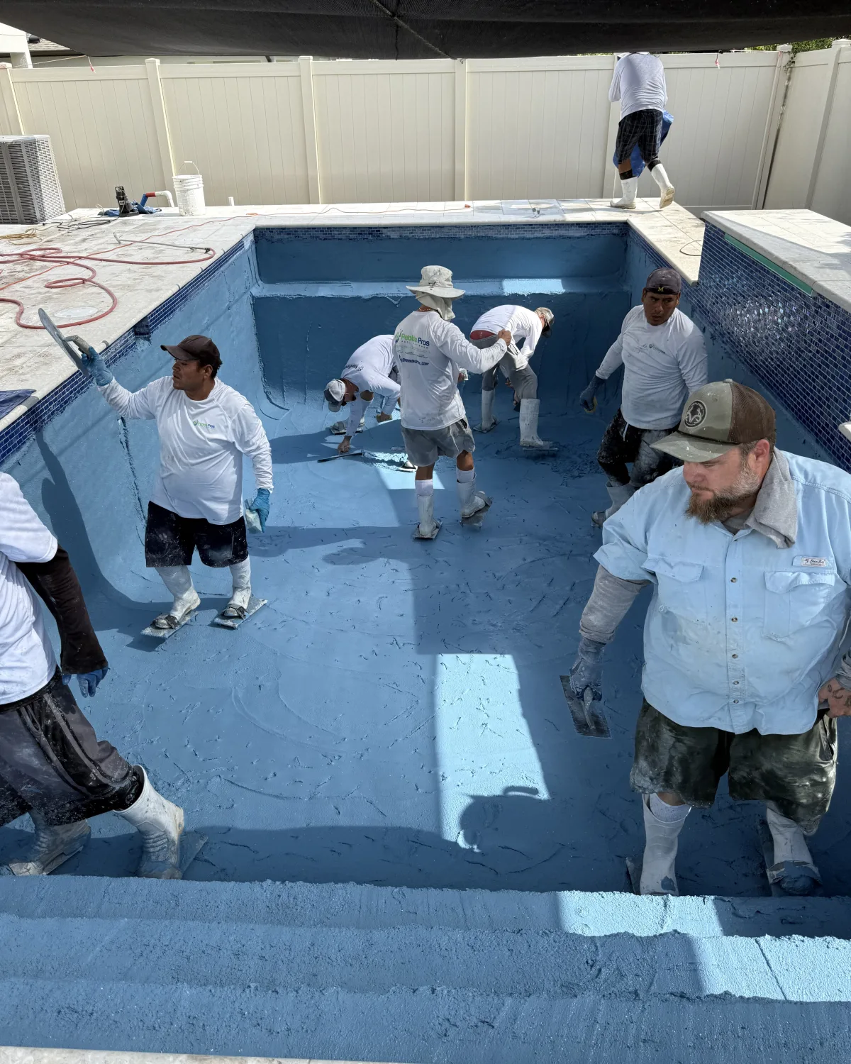 Shotcrete pool construction in progress, crew applying concrete in a Tampa Bay backyard