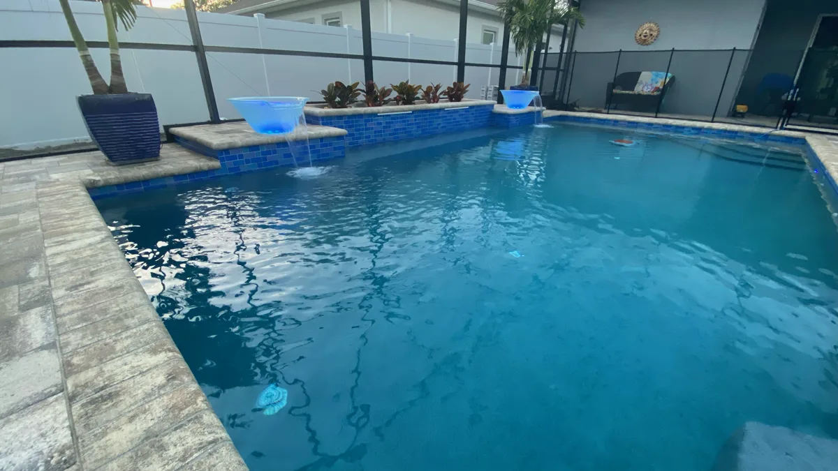 Custom pool with blue mosaic waterline tile, LED fire bowls, and cascading water features, Tampa FL