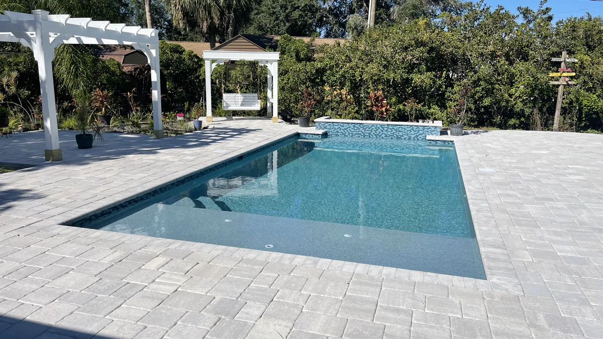 Custom pool with white pergola, covered gazebo, and expansive paver patio, Tampa FL