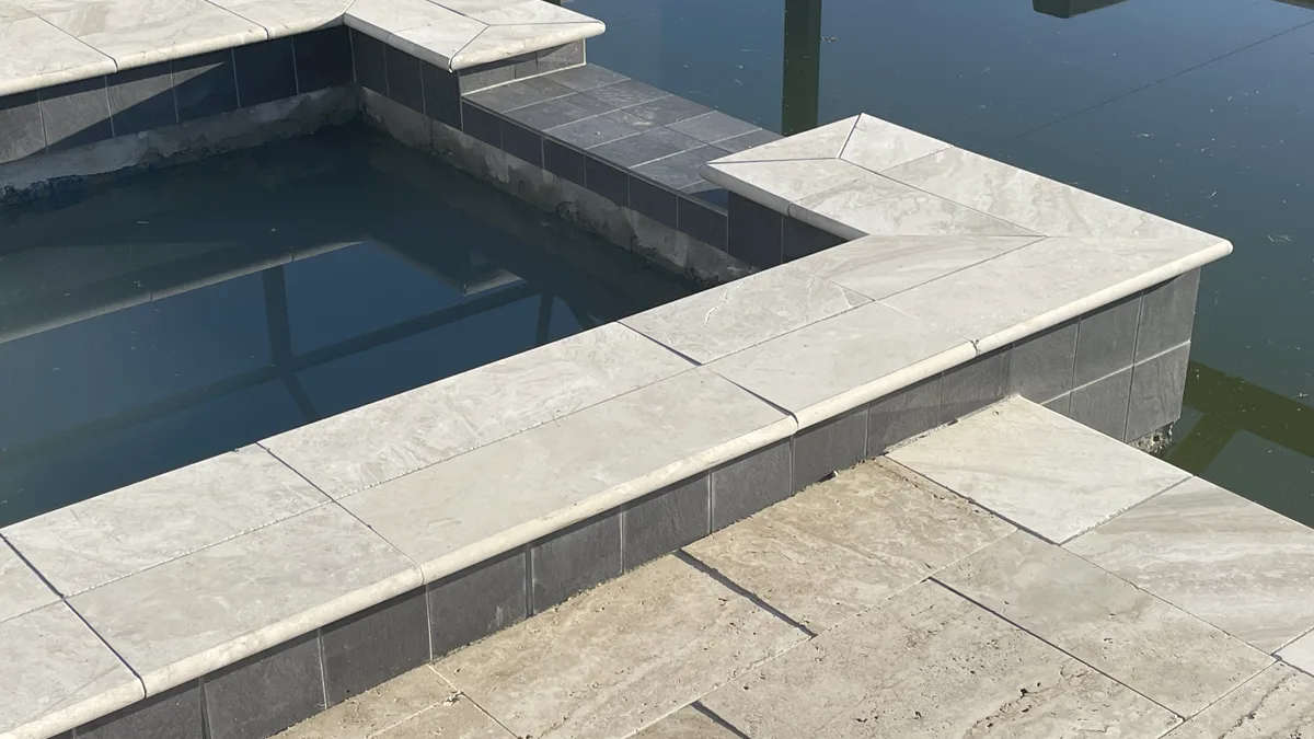 French-pattern travertine coping with dark mosaic accent tile and pool water detail, Pinellas County FL