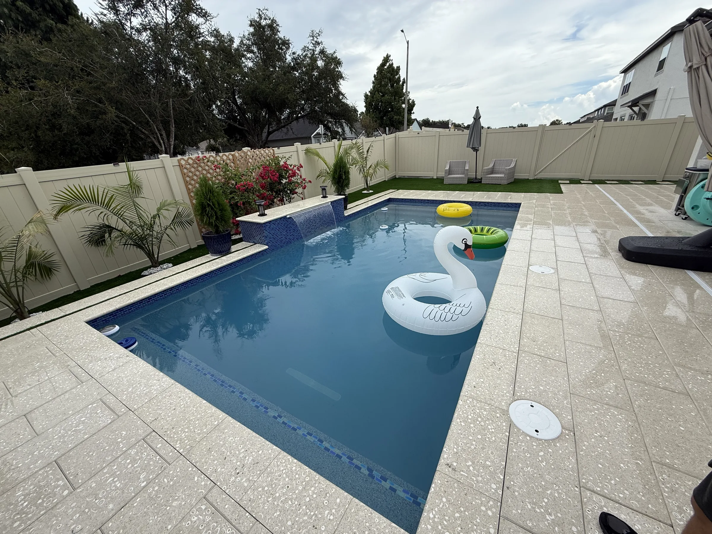 Screen-enclosed rectangular blue pool with paver deck and turf, Trinity FL