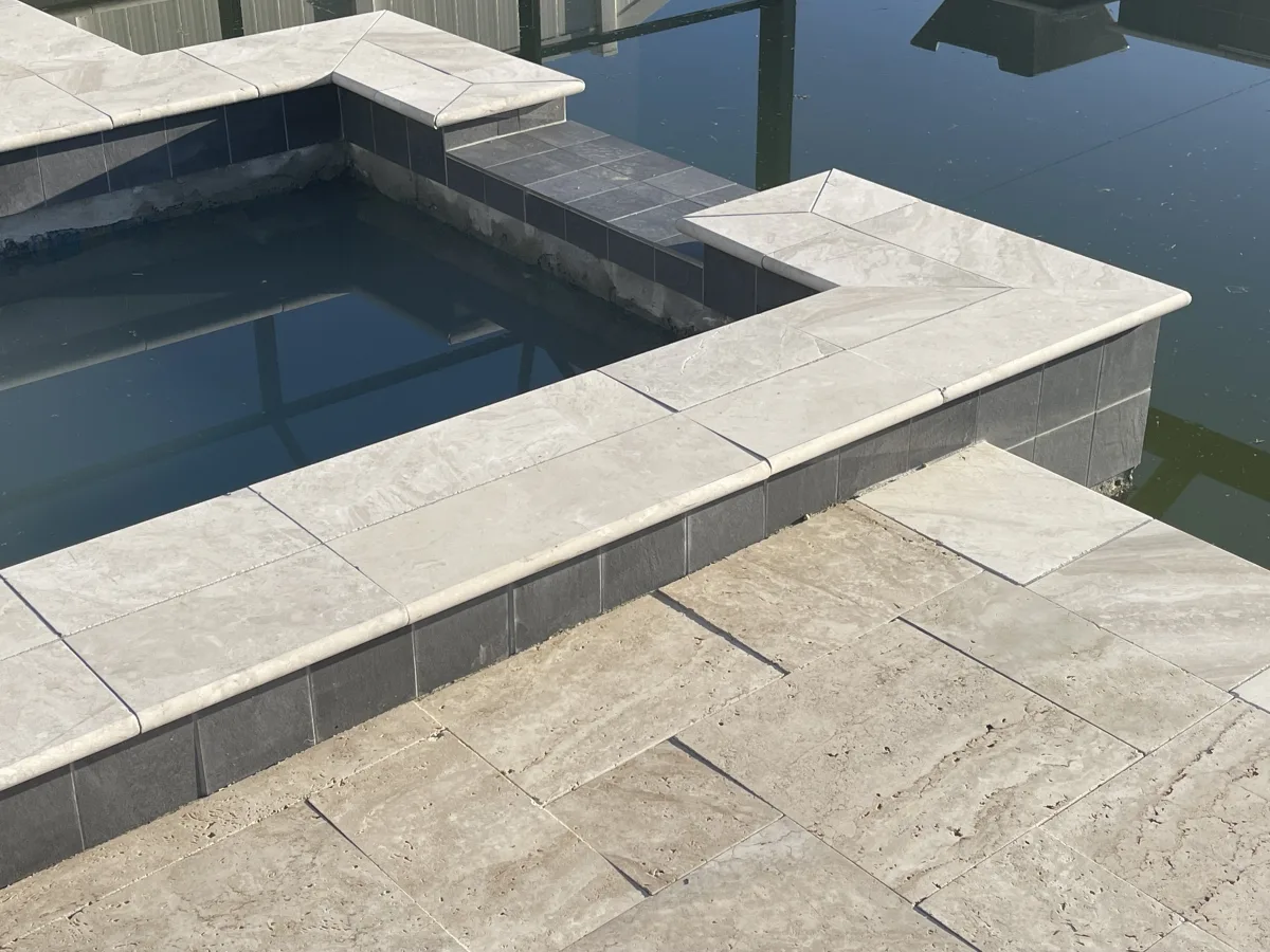 French-pattern travertine coping with dark mosaic accent tile and pool water detail, Pinellas County FL