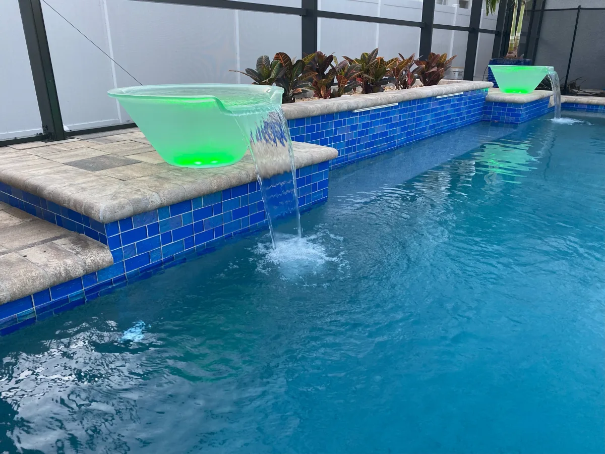 Custom pool with LED fire bowls and cascading water features at dusk, Tampa FL